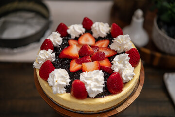 Delicious cheesecake topped with fresh strawberries and whipped cream displayed on a wooden table at a cozy cafe