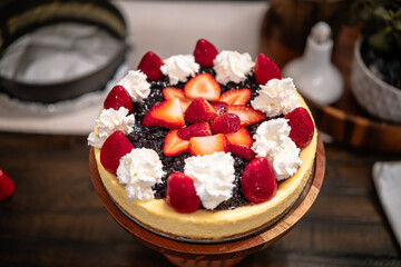Delicious cheesecake topped with fresh strawberries and raspberries presented on a wooden pedestal