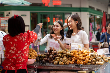 Two Women Enjoying Street Food at a Bustling Market in urban