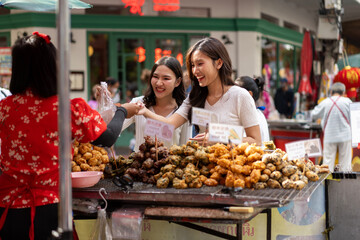 Two Women Enjoying Street Food at a Bustling Market in urban