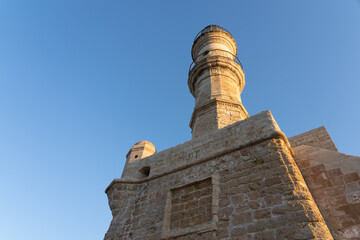 Obraz premium Medieval Lighthouse and end of long stone breakwater and walk at Chania at sunrise