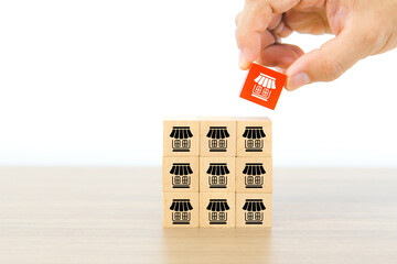Hand chooses franchise business store icons on cube wooden toy block stack in pyramid for...