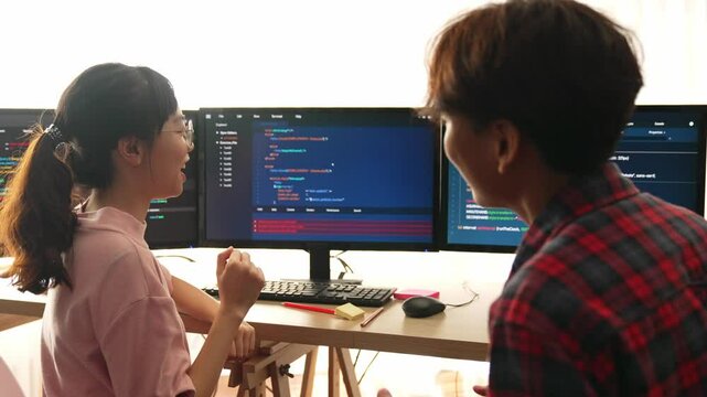 Slow motion back end software developer engineer for computer programming working together on debugging writing computing code, solving complex algorithms display on monitor in office. Burgeoning