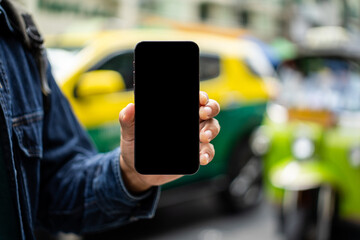 Asian traveling backpacker in Khao San Road outdoor market in Bangkok Thailand. Using mobile phone application to navigate the location. Tourist walking in the downtown street traditional market