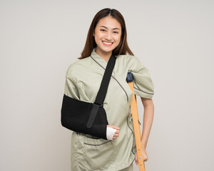 Happy young asian woman broken arm on isolated background. Asian female put on plaster bandage cast splint. Patient wearing sling support arm after accident injury. life insurance and accident