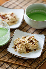 Cup of fresh matcha tea and Warabi mochi, traditional Japanese sweet from bracken starch on wooden table.