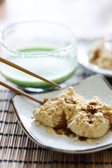 Cup of fresh matcha tea and Warabi mochi, traditional Japanese sweet from bracken starch on wooden table.
