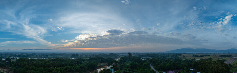 A breathtaking sunrise illuminates a small village nestled among lush green fields and karst mountains, with vibrant clouds filling the sky. The harmony of rural life set dramatic natural formations.