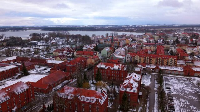 Snow over Elk city with St Wojciech Cathedral in view near Elk Lake, Vibrant colourful apartment buildings and neighbourhood in winter landscape, Establishing drone shot
