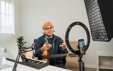 Professional Musician with condenser microphone and tablet for Mixing Mastering music. Music composer male composing a song with guitar and piano keyboard at digital Recording home studio