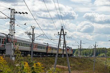 An electric train traveling on railway tracks under a sunny sky, transportation concept