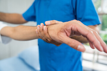 Physical therapy. Male Nurse aids young man in recovering from spine injury and providing...