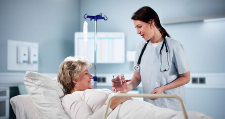 Fototapeta premium Happy Female Doctor Giving Glass Of Water To Senior Woman