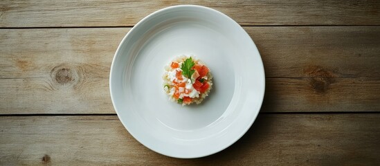 Minimalistic dish on a white plate centered against a rustic wood background highlighting themes of simplicity and insufficient nourishment.