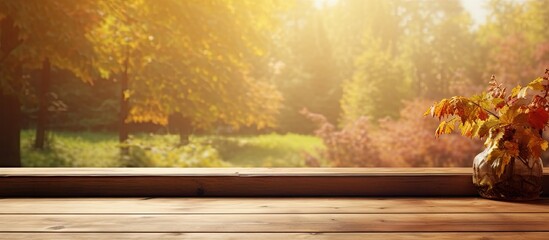 Sunlit wooden table with golden leaves on a sunny autumn day, positioned in front of a bright window with warm foliage in the background.