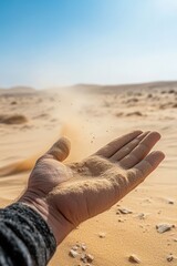 A hand gently rests on a sand dune, grains trickling away beneath it as it basks in the warmth of daylight, surrounded by an expansive desert under a brilliant blue sky