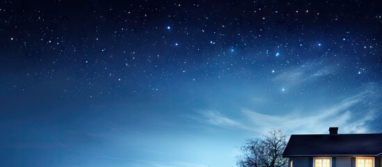 Naklejka premium Serene night sky filled with twinkling stars above a cozy house with warm light glowing from a window trees silhouette in deep blue hues.