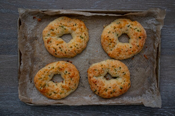Cooked four homemade jalapeno cheese bagels, parchment paper on wood.
