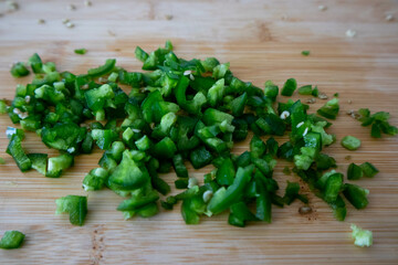 Diced green jalapeno pepper on wood cutting board.