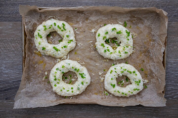 Four homemade jalapeno cheese bagels, parchment paper on wood.