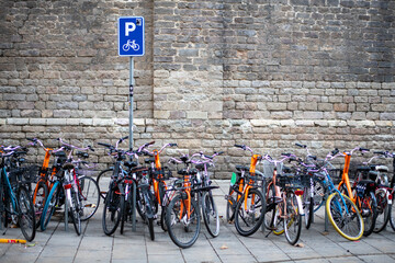 Bikes bicycles parked in front of a stone wall on a Barcelona sidewalk © Cavan