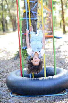 A happy child in overalls hangs upside down on colorful bars out