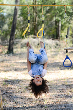 A cheerful child in overalls hangs upside down on yellow playgro