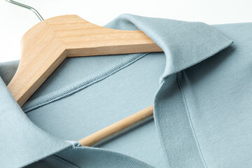 Closeup view of light blue cotton men polo shirt, collar part with wooden hanger
