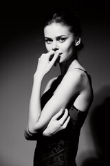 Fototapeta premium Elegant woman in a black dress posing thoughtfully against a dark background, showcasing beauty and confidence. Fashion and portrait concept.