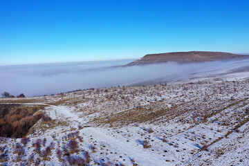 Aerial view of misty countryside hills at wintertime, morning fog above