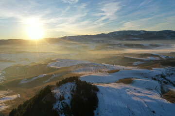 Aerial view of sunset over misty winter mountains