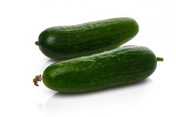 Fresh and vibrant cucumbers resting on a clean white surface in a natural light setting