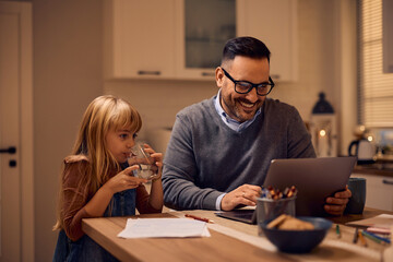 Happy father working on computer while being with his daughter at home.