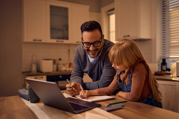 Happy father assisting his daughter in doing homework while e-learning at home.