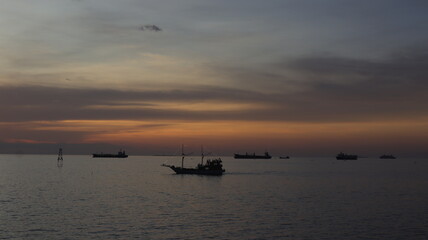 Low orange sunset in dramatic clouds over ocean in Indonesia