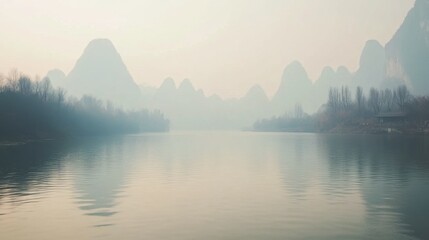 Serene River Landscape:  A mist-shrouded river flows gently past the iconic karst mountains, creating a breathtaking and ethereal vista in a scene reminiscent of a timeless Chinese landscape painting.