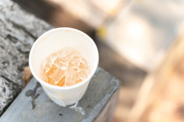 Disposable cup with clear ice cubes on a textured surface, creating a refreshing and minimalist scene.