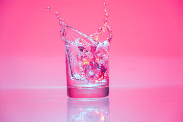 ice cube falling into glass of water with splash 