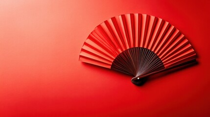 Elegant red fan displayed on a vibrant crimson background, showcasing intricate folds and design during a cultural event