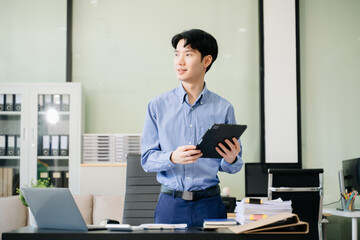Young business man working at office with laptop, tablet and taking notes