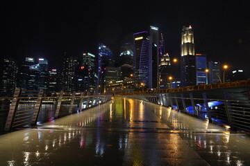 Obraz premium Marina Bay Sands lights up Singapore’s skyline at night with its glowing towers and rooftop, showcasing stunning modern architecture above the shimmering Marina Bay. 