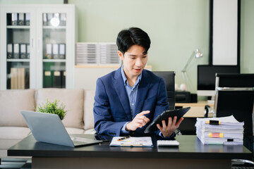 Young business man working at office with laptop, tablet and taking notes