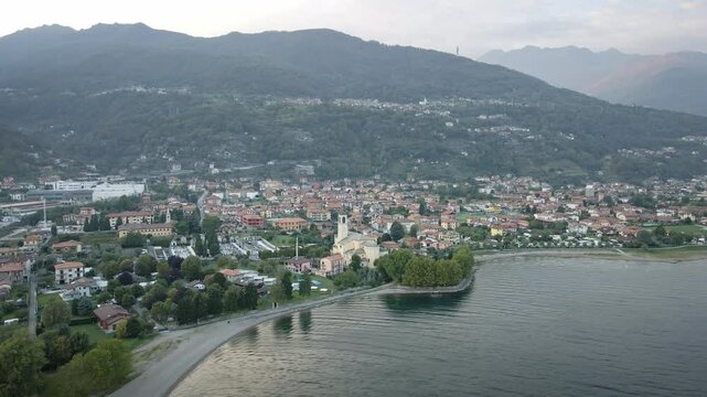 A beautiful drone shot from Dongo in Lake Como, flying towards the picturesque town. The shot captures the charming architecture, serene waterfront, and majestic mountain backdrop.