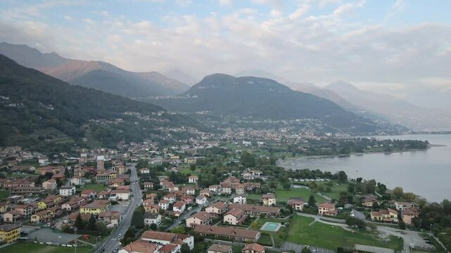 A captivating drone shot of the Italian town Dongo in Lake Como, captured from a unique angle. The footage highlights the town, majestic mountains, and serene waterfront scenery.