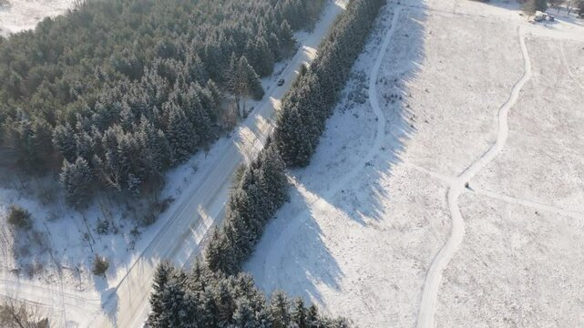 Flyover drone shot of snowy sideroad and forest in Caledon, Ontario, Canada