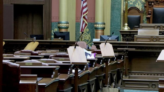 Michigan House of Representatives chamber inside the Michigan state capitol with low view of empty desks and stable video.
