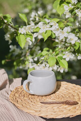 Delicate white flowers and a cup on a woven mat in a sunny garden