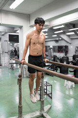 Fototapeta premium Asia young man warm up or exercising on parallel bars at gym
