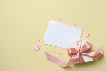 Beautiful gift box with pink hearts and paper card on color background