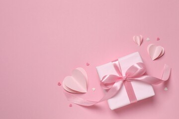 Beautiful gift box with pink hearts on color background